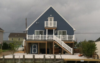 A blue house with a deck on the water.