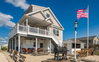 A beach house with an american flag on the beach.