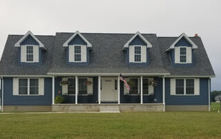 A blue house with white trim and a flag on the front porch.