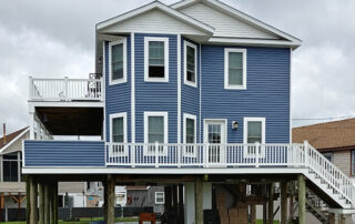 A blue house with a deck on top of it.