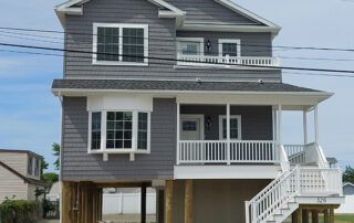 A gray house with a white porch and stairs.
