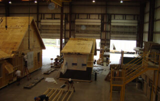 A group of people working on a house in a warehouse.