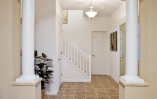 A hallway in a home with columns and carpet.