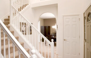 A white staircase in a home with a chandelier.