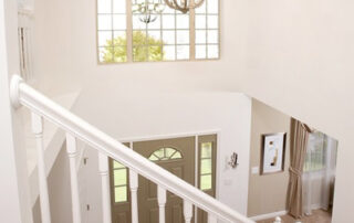 A white staircase with a chandelier in the middle.