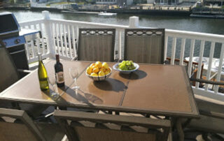 A deck with a table and chairs and a bottle of wine.