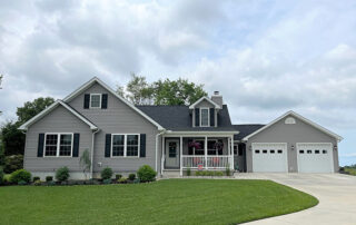 A gray home with a large front yard.