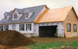 A house under construction with a dirt driveway.