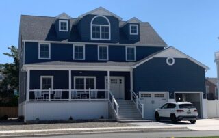 Two-story blue coastal house with a white mini-van in the driveway