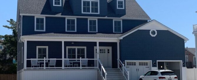 Two-story blue coastal house with a white mini-van in the driveway