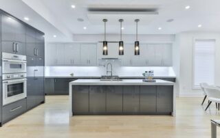 A open kitchen design with a white marble slab island counter, white cabinets and matte black hanging lights over the island